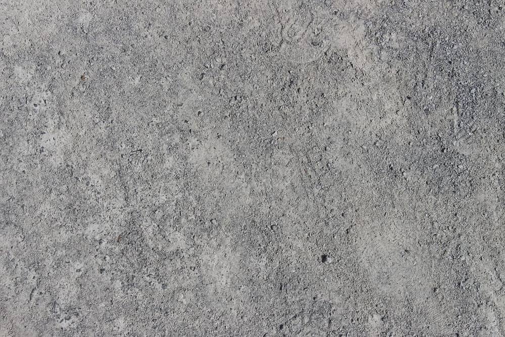Gros plan sur une dalle de béton brut non traitée, surface grise et granuleuse