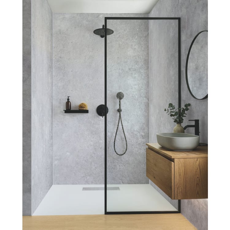 Douche a l italienne dont les trois parois sont couvertes de dalles murales PVC effet beton, avec receveur blanc et paroi vitree a profile noir.