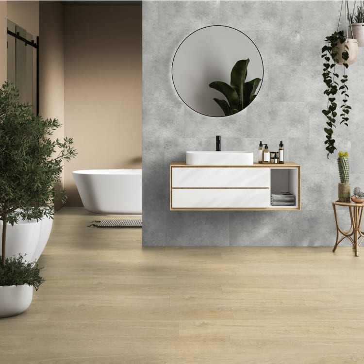 Salle de bain dont le mur de la vasque est habille de dalles murales PVC effet beton gris clair, face a une baignoire ilot.