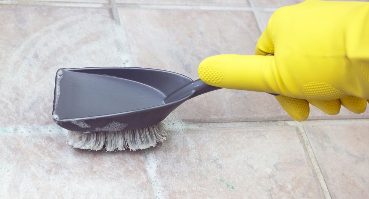 personne qui nettoie des joints de carrelage avec une brosse