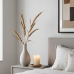 Chambre parentale minimaliste décorée avec des accessoires soigneusement sélectionnés, comme un vase avec une seule branche de fleurs séchées, une bougie parfumée et un tableau abstrait.