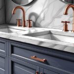 Double vasque de salle de bain avec robinetterie cuivrée sur un meuble bleu marine, le tout surmonté d'un plan de travail en marbre dans une salle de bain moderne.